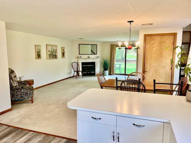 kitchen featuring hanging light fixtures, an inviting chandelier, visible vents, baseboards, and a glass covered fireplace