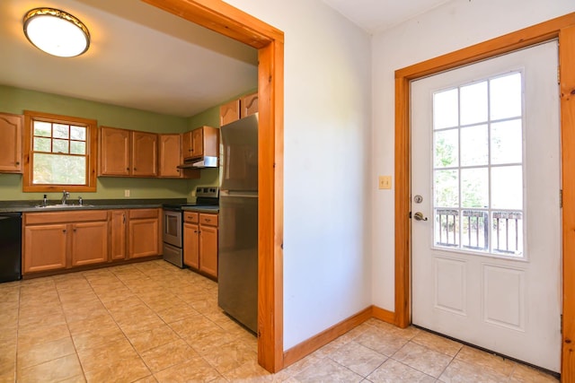 kitchen with light tile patterned floors, a sink, dark countertops, baseboards, and appliances with stainless steel finishes