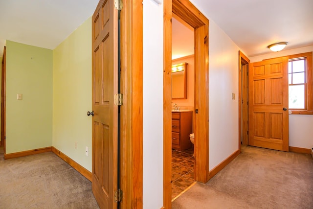 corridor featuring carpet flooring, baseboards, and a sink