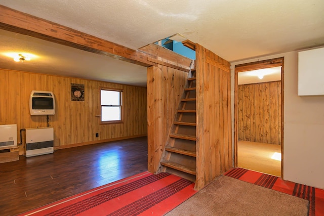 below grade area with heating unit, wooden walls, and wood finished floors