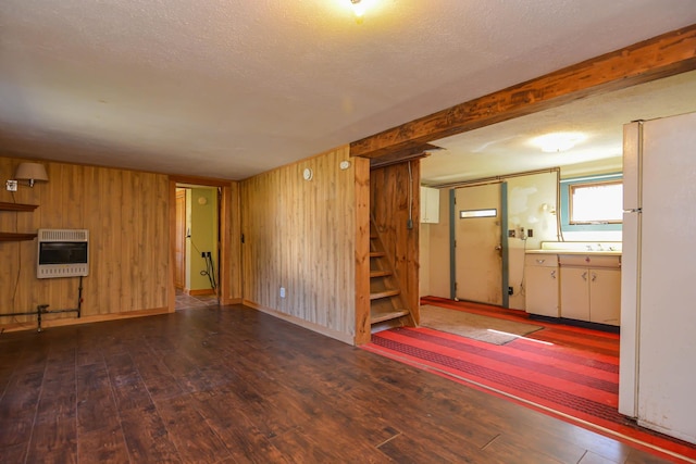 unfurnished living room featuring stairs, wood walls, heating unit, and hardwood / wood-style flooring