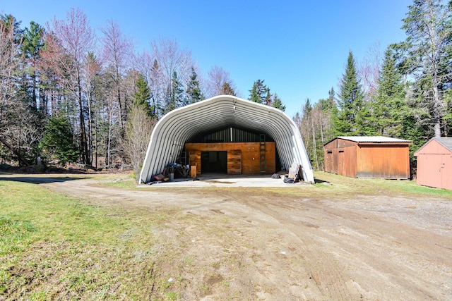 view of parking / parking lot with dirt driveway, a detached carport, and a shed