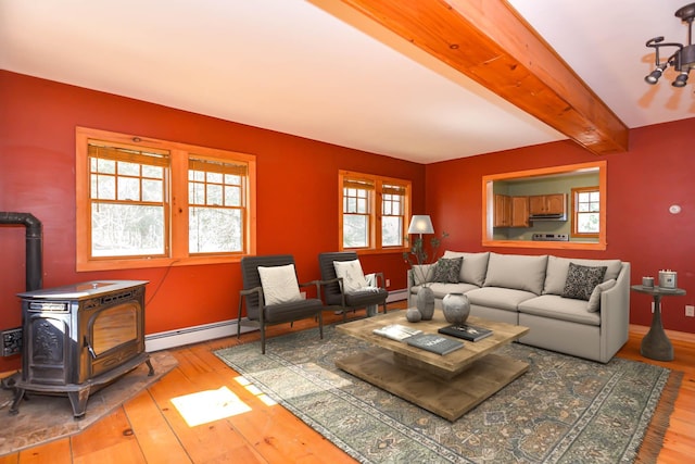 living room featuring a baseboard heating unit, beamed ceiling, a wood stove, and wood-type flooring
