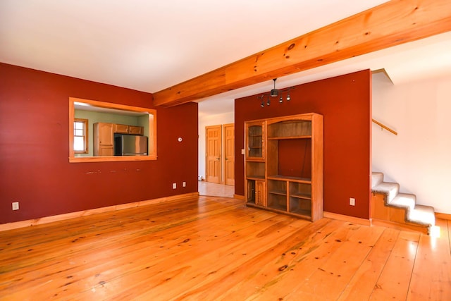 unfurnished living room featuring hardwood / wood-style flooring, stairs, and baseboards
