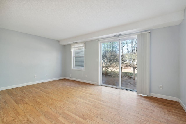 unfurnished room with baseboards, light wood-style floors, and a textured ceiling