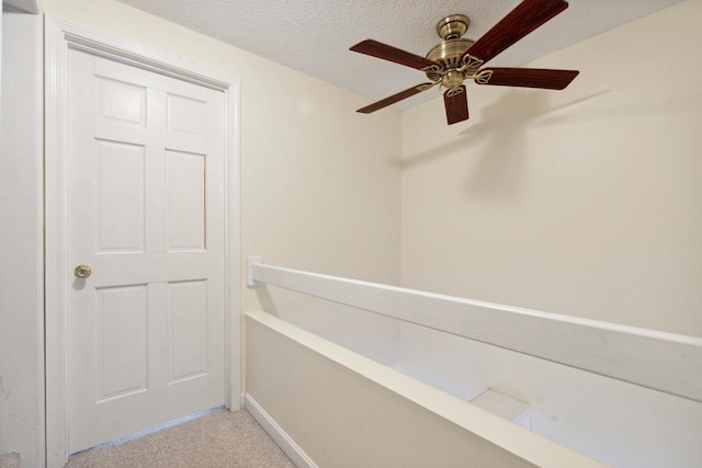 interior space featuring light colored carpet, a textured ceiling, baseboards, and ceiling fan