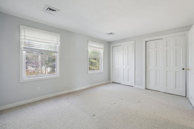 unfurnished bedroom with carpet, baseboards, and multiple closets