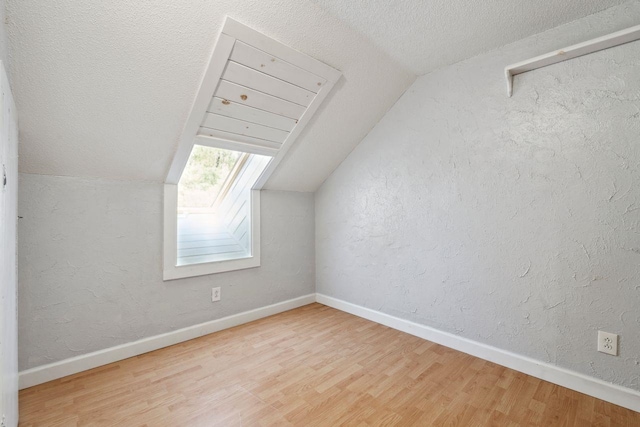 bonus room featuring vaulted ceiling, a textured ceiling, baseboards, and wood finished floors