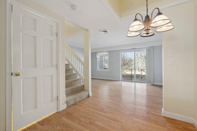 entrance foyer with a chandelier, light wood-style floors, visible vents, and baseboards