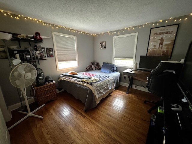 bedroom with multiple windows, a textured ceiling, baseboards, and hardwood / wood-style floors