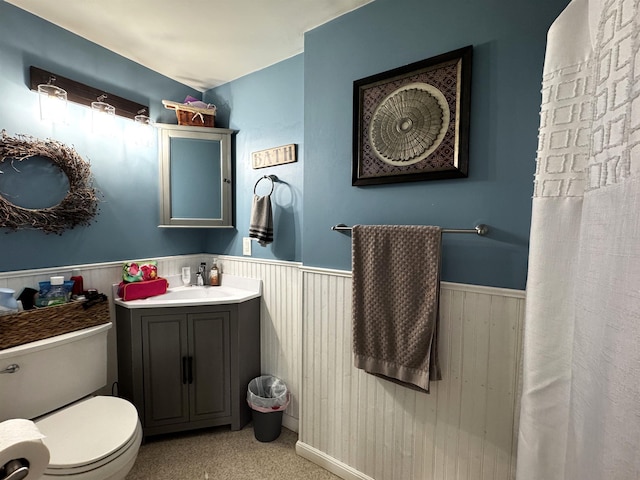 full bath featuring vanity, wainscoting, and toilet