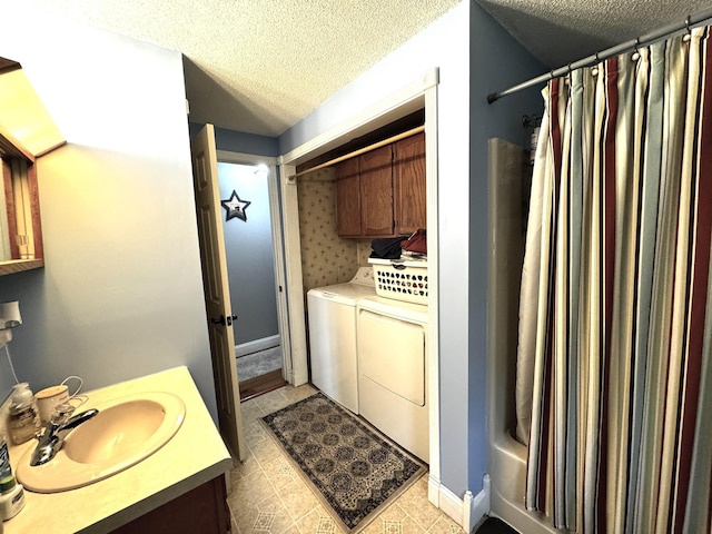 bathroom featuring washing machine and clothes dryer, a textured ceiling, and vanity