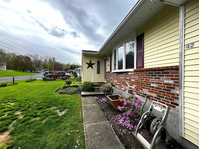 view of side of home featuring a lawn and brick siding