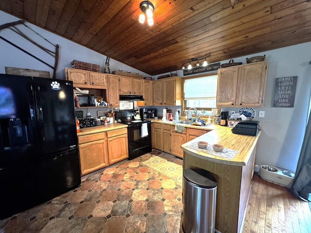 kitchen featuring a sink, black appliances, vaulted ceiling, under cabinet range hood, and light countertops