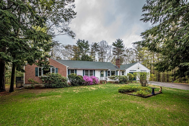 ranch-style home with a front yard, a chimney, a garage, and aphalt driveway