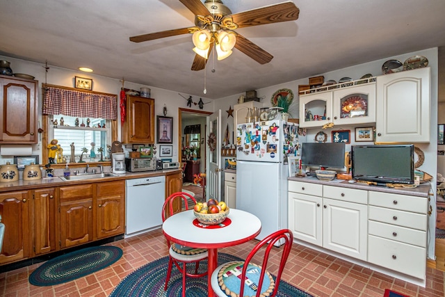 kitchen with glass insert cabinets, a ceiling fan, a sink, white appliances, and brick patterned floor