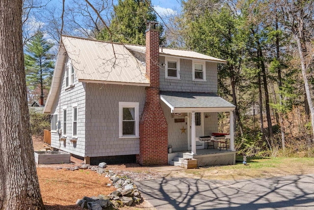 view of front facade featuring covered porch and a chimney