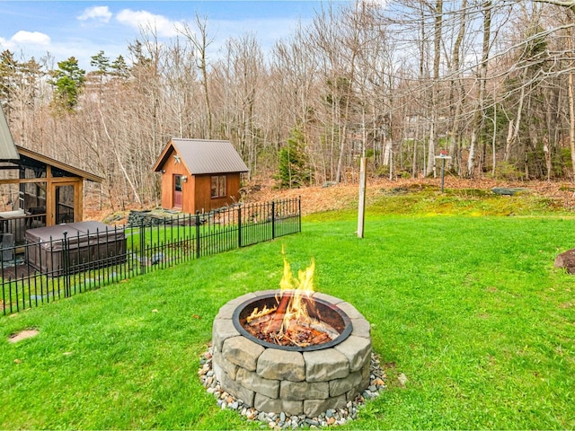 view of yard featuring a fire pit, an outbuilding, fence, and a view of trees