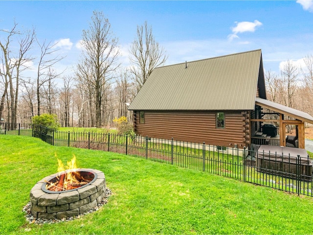 view of side of home with an outdoor fire pit, fence, log exterior, and a lawn