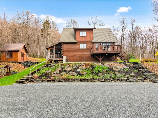 view of front of property featuring log siding, metal roof, a sunroom, a deck, and stairway