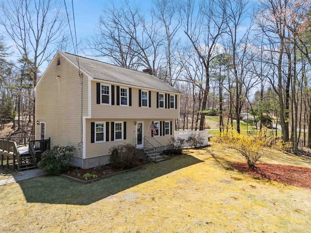 colonial-style house with a front lawn, a chimney, and a deck