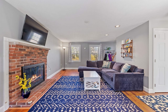 living area featuring baseboards, a fireplace, recessed lighting, and wood finished floors
