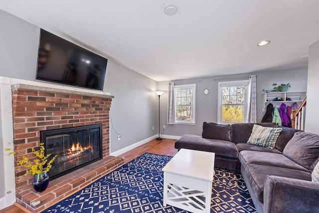 living room featuring recessed lighting, a brick fireplace, baseboards, and wood finished floors