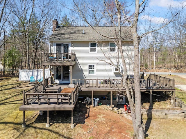 rear view of property with a chimney, a deck, roof with shingles, and a balcony