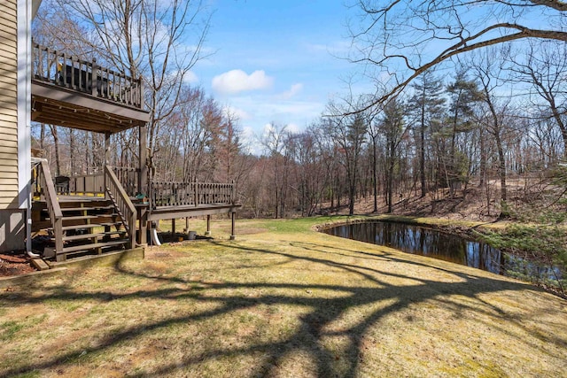 view of yard with a balcony, stairway, and a deck with water view