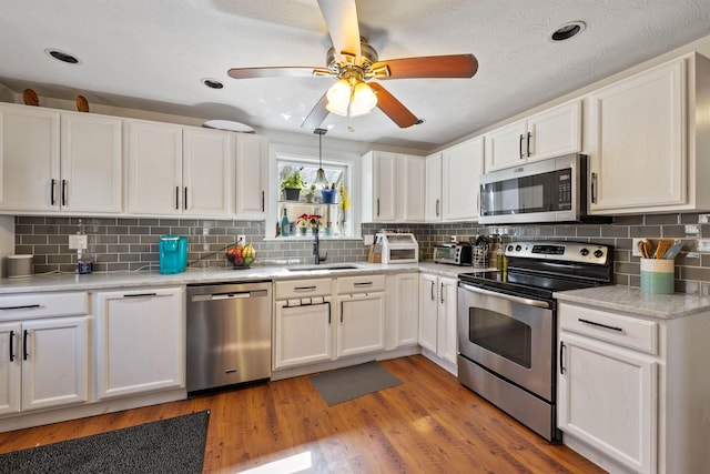 kitchen with a sink, white cabinetry, light countertops, and appliances with stainless steel finishes