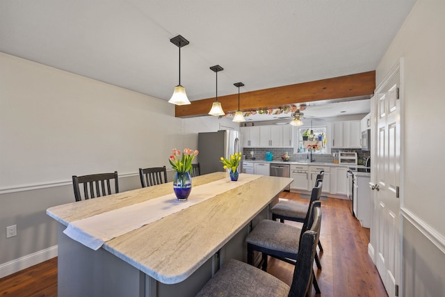 dining area featuring baseboards, dark wood-style flooring, and a ceiling fan