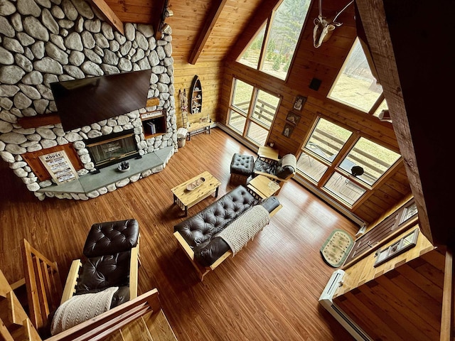 93 Roller Coaster Rd, Laconia, NH 03246 - living room featuring wooden ceiling, wooden walls, wood finished floors, a stone fireplace, and beam ceiling