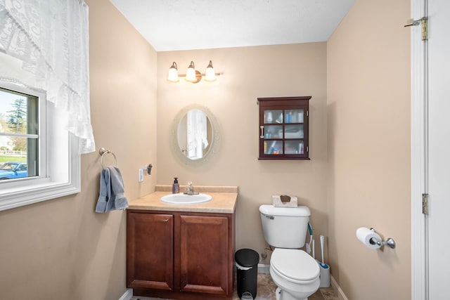 bathroom with toilet, baseboards, and vanity