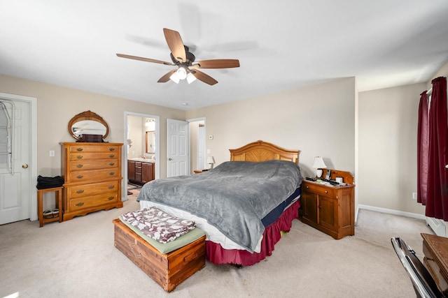 bedroom featuring light colored carpet, a ceiling fan, ensuite bath, and baseboards