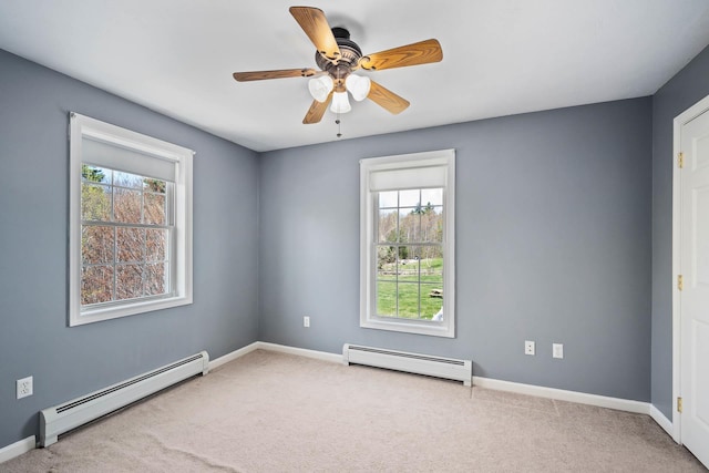 carpeted empty room with a baseboard heating unit, a ceiling fan, and baseboards