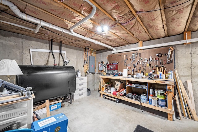 unfinished basement with oil tank, electric panel, and a workshop area