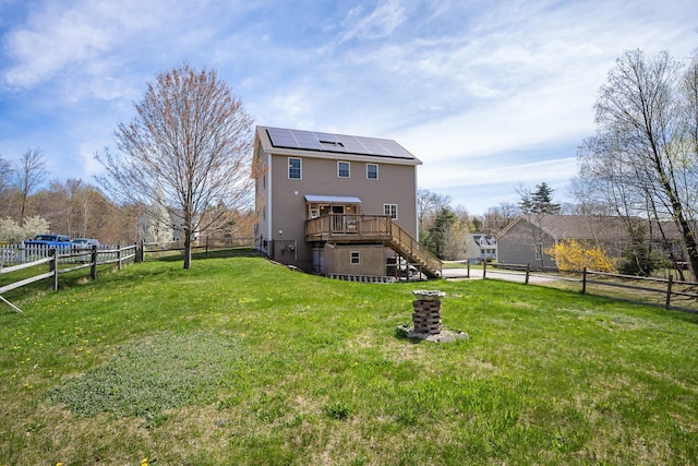 back of property with stairs, a deck, and roof mounted solar panels
