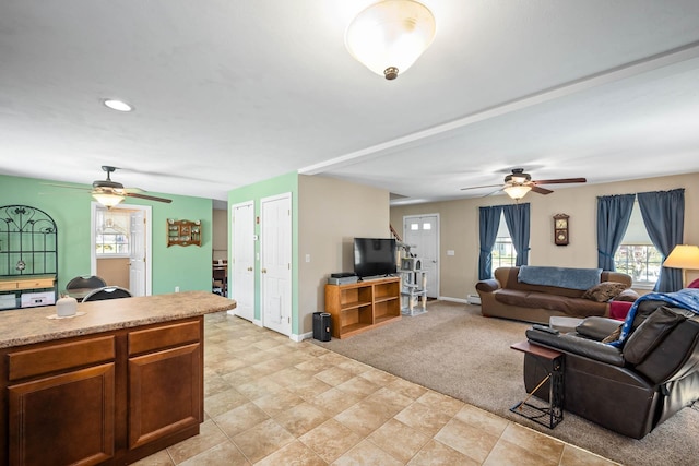 living area featuring ceiling fan, healthy amount of natural light, and baseboards