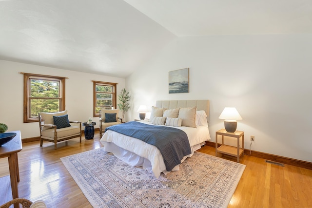 bedroom featuring lofted ceiling, baseboards, and wood finished floors