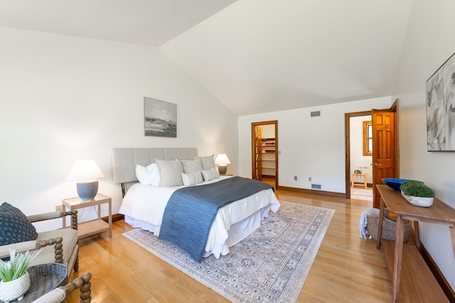 bedroom with lofted ceiling, light wood finished floors, and baseboards