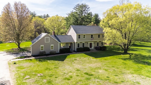 colonial home featuring a front yard and a chimney