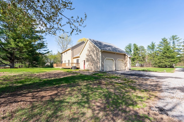 view of property exterior featuring a garage, a wooden deck, and a yard