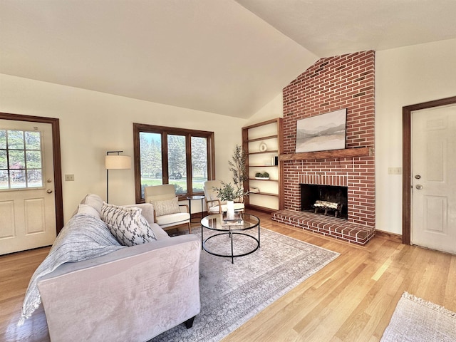 living area with wood finished floors, a brick fireplace, and vaulted ceiling