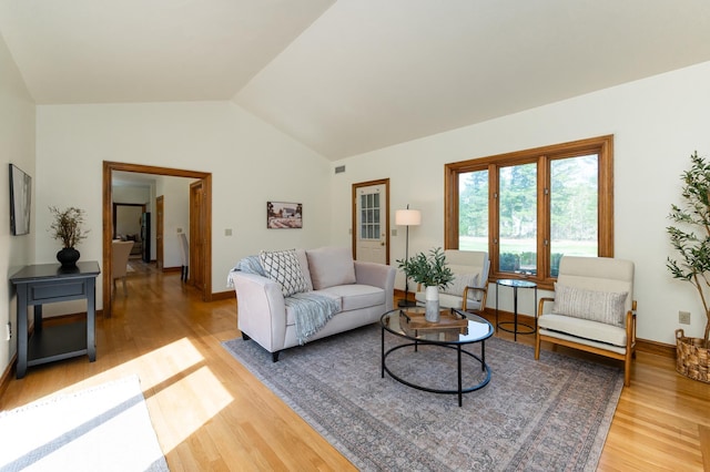 living area with light wood-style flooring, lofted ceiling, and baseboards