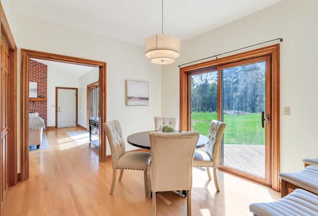 dining room featuring light wood finished floors, lofted ceiling, and baseboards