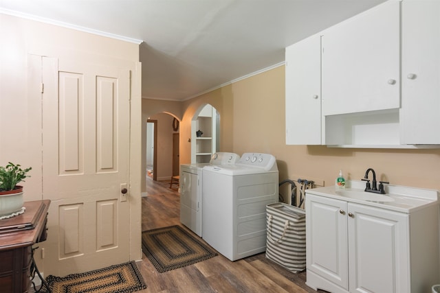 clothes washing area featuring separate washer and dryer, arched walkways, dark wood finished floors, crown molding, and cabinet space
