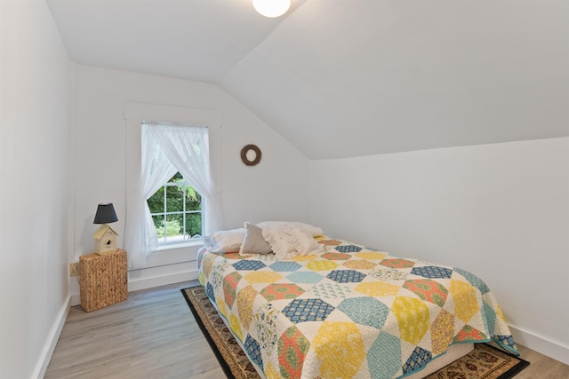 bedroom with wood finished floors, lofted ceiling, and baseboards