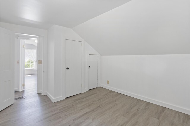 bonus room featuring light wood-style floors, vaulted ceiling, and baseboards