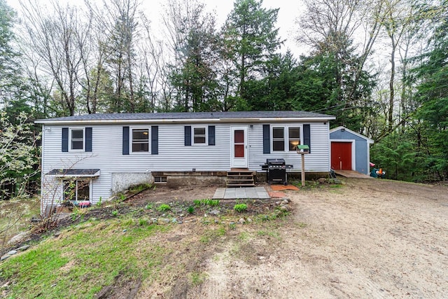 manufactured / mobile home with a storage unit, an outdoor structure, view of scattered trees, and a detached garage