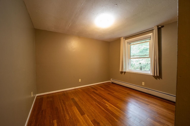 unfurnished room featuring a baseboard radiator, wood finished floors, baseboards, and a textured ceiling